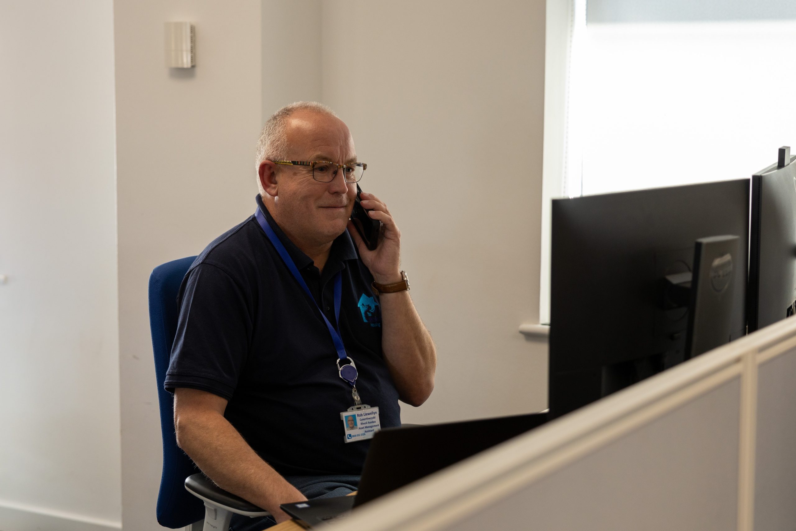 member of staff answering phone call while sat at desk looking at computer